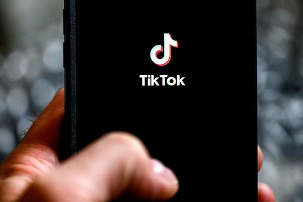 A hand holds a mobile phone with the TikTok logo on the screen.