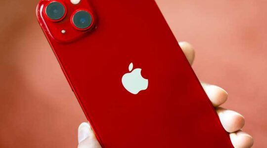 A hand holds a red iPhone