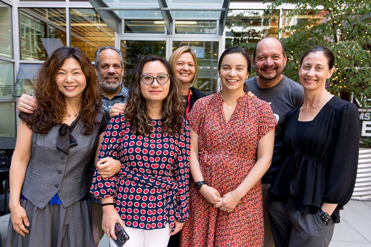 Seven members of the Khoury global network pose for a photo in a courtyard at Northeastern Seattle.