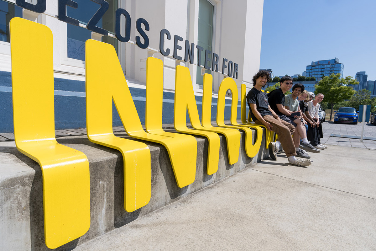 Students sit on a sign at Northeastern's campus