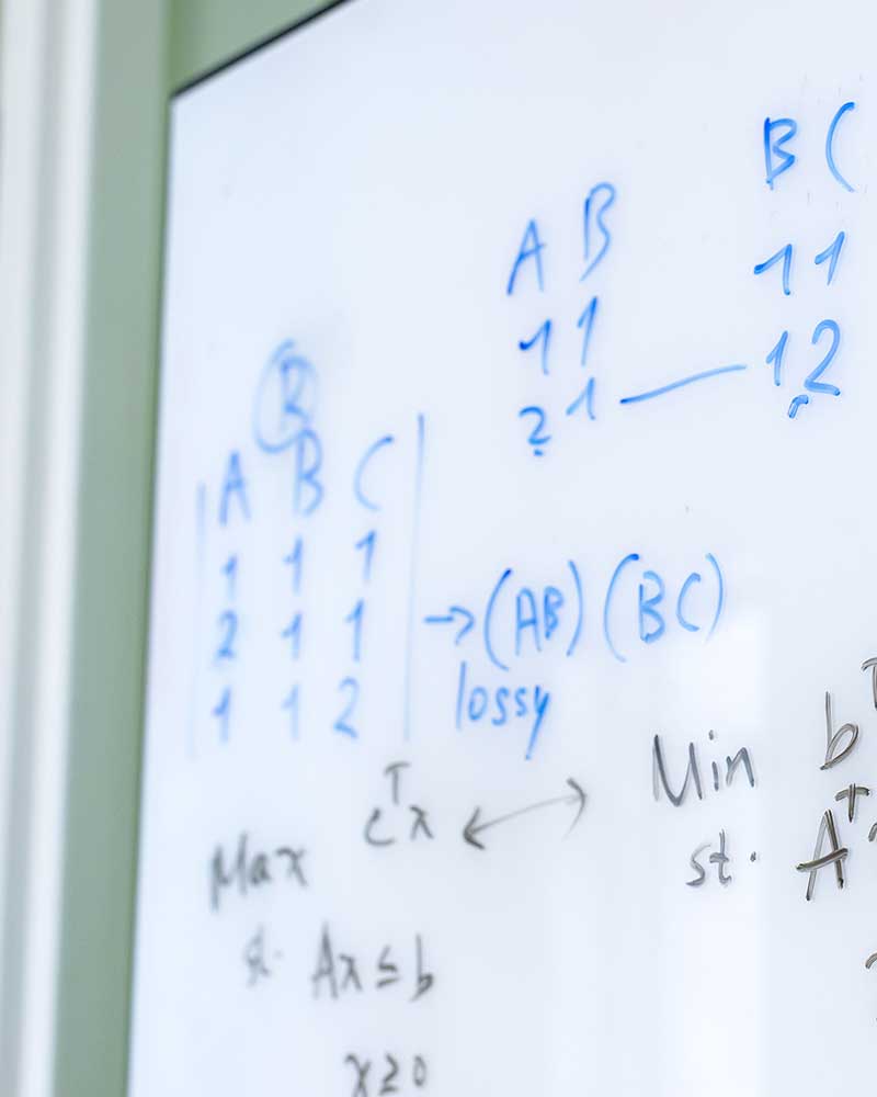 A whiteboard with different mathematical variables and notes written in blue and black