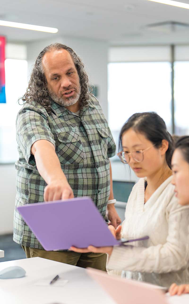 Khoury faculty member Albert Lionelle points at a student's laptop screen during a class session