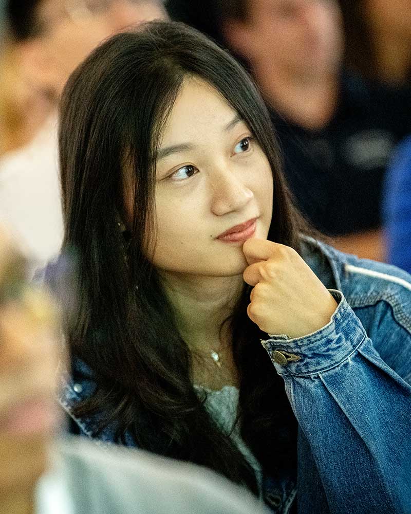 A student rests her chin on her hand while intently watching a presentation