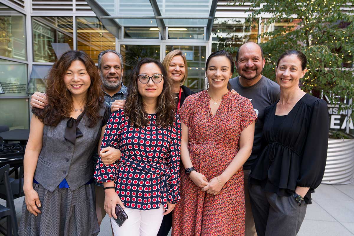 A group of seven Khoury faculty and staff pose for a photo in a courtyard at Northeastern Seattle