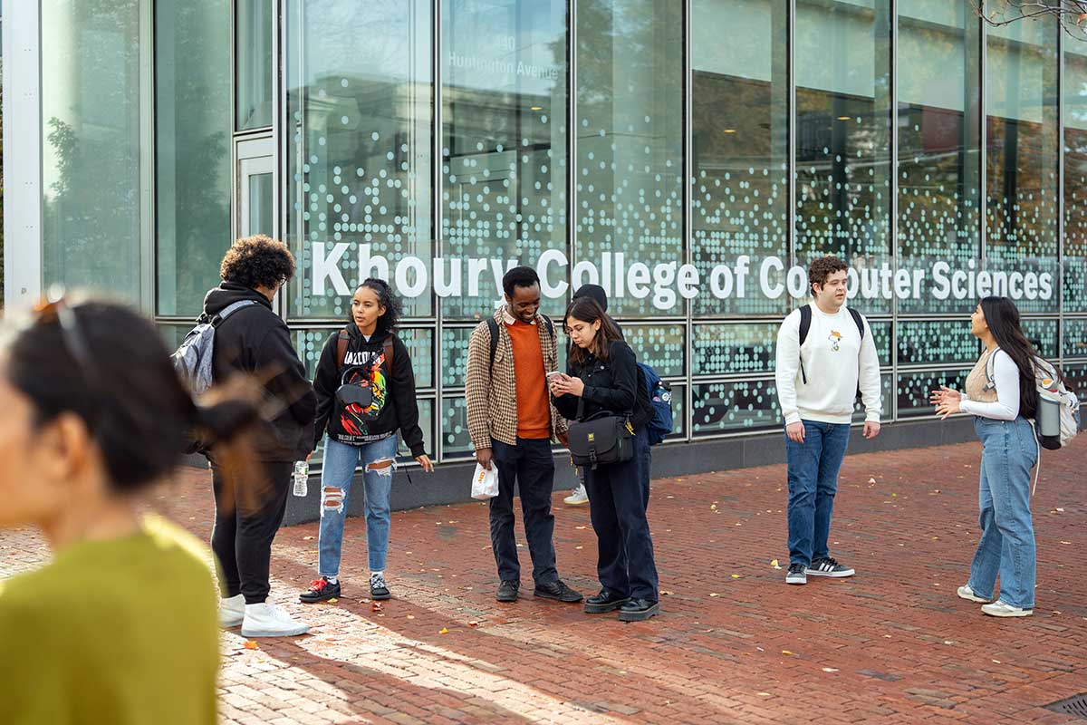 Seven Khoury students stand on brick sidewalk outside West Village H at Northeastern's Boston campus