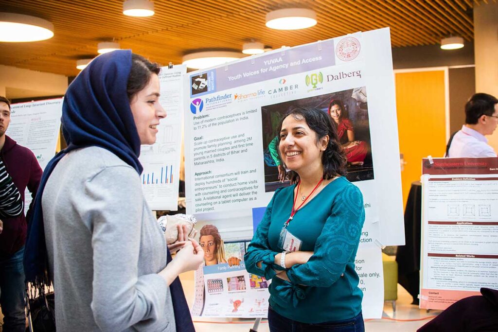 Two students discuss a research poster at a research expo