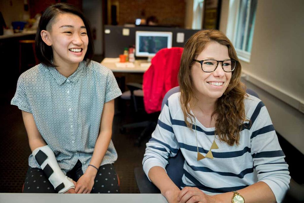 Two women smile as they work