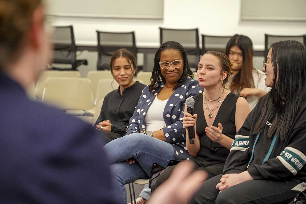 A female student asks a question while holding a microphone during a campus event