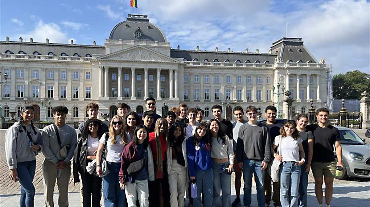 Students pose for a photo in front of a Belgian landmark