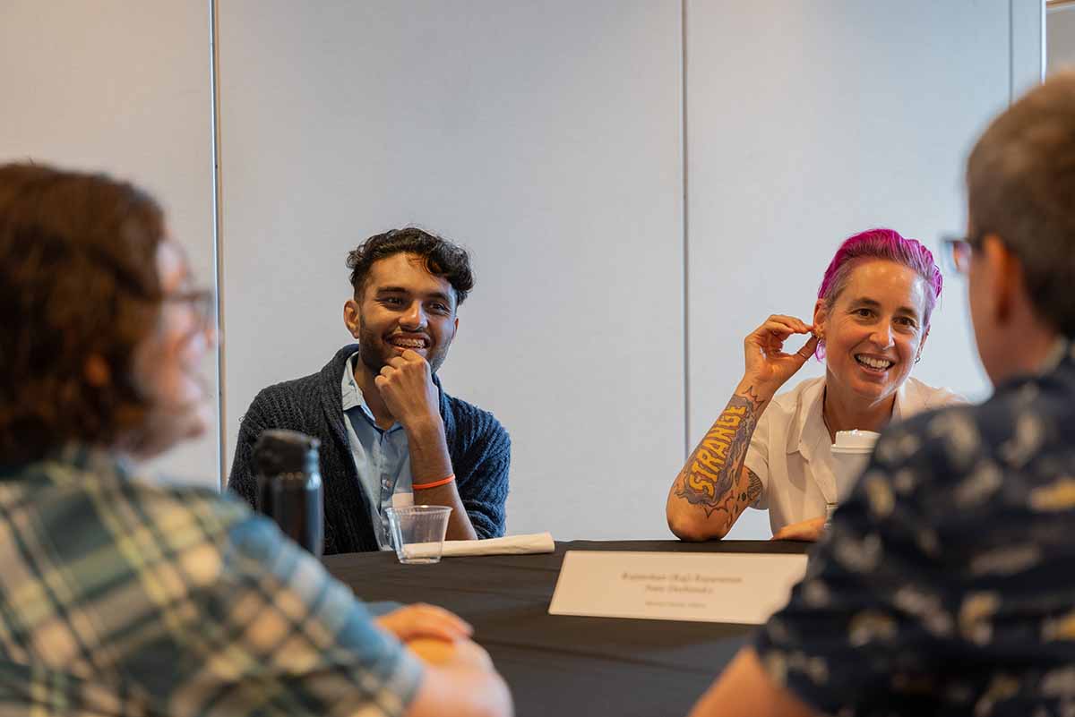 People cheerfully discuss at a roundtable meeting.