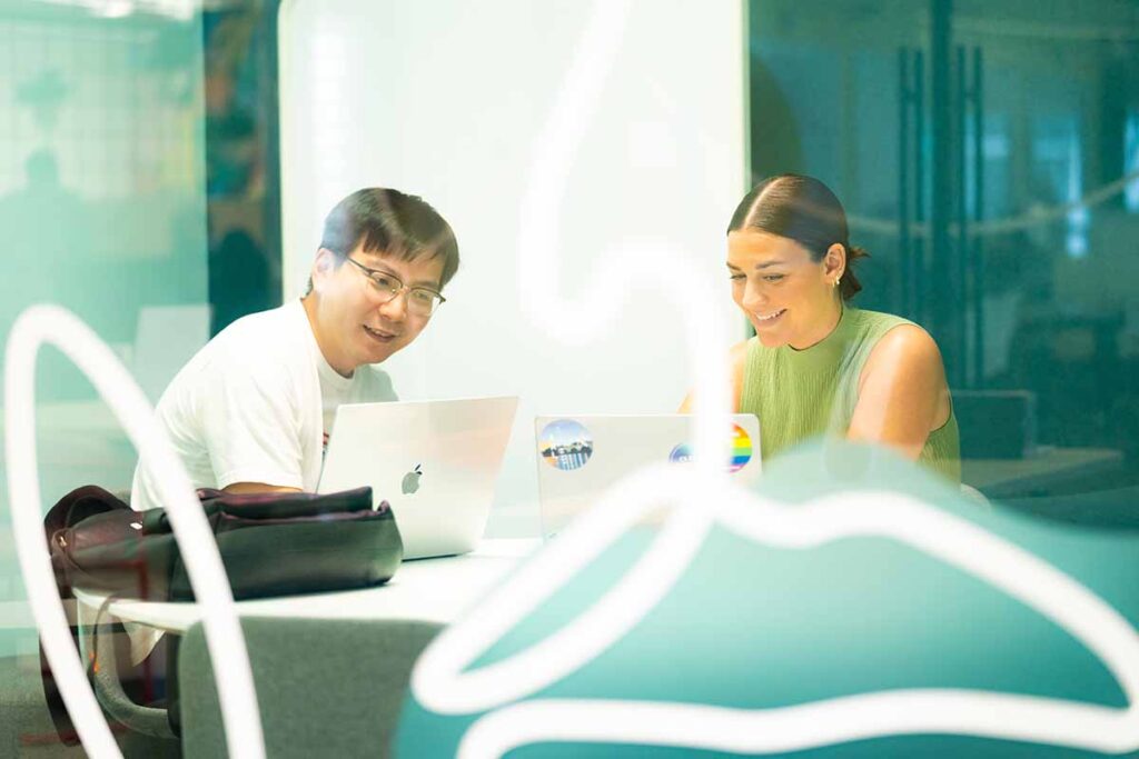 Two students discuss work at a table