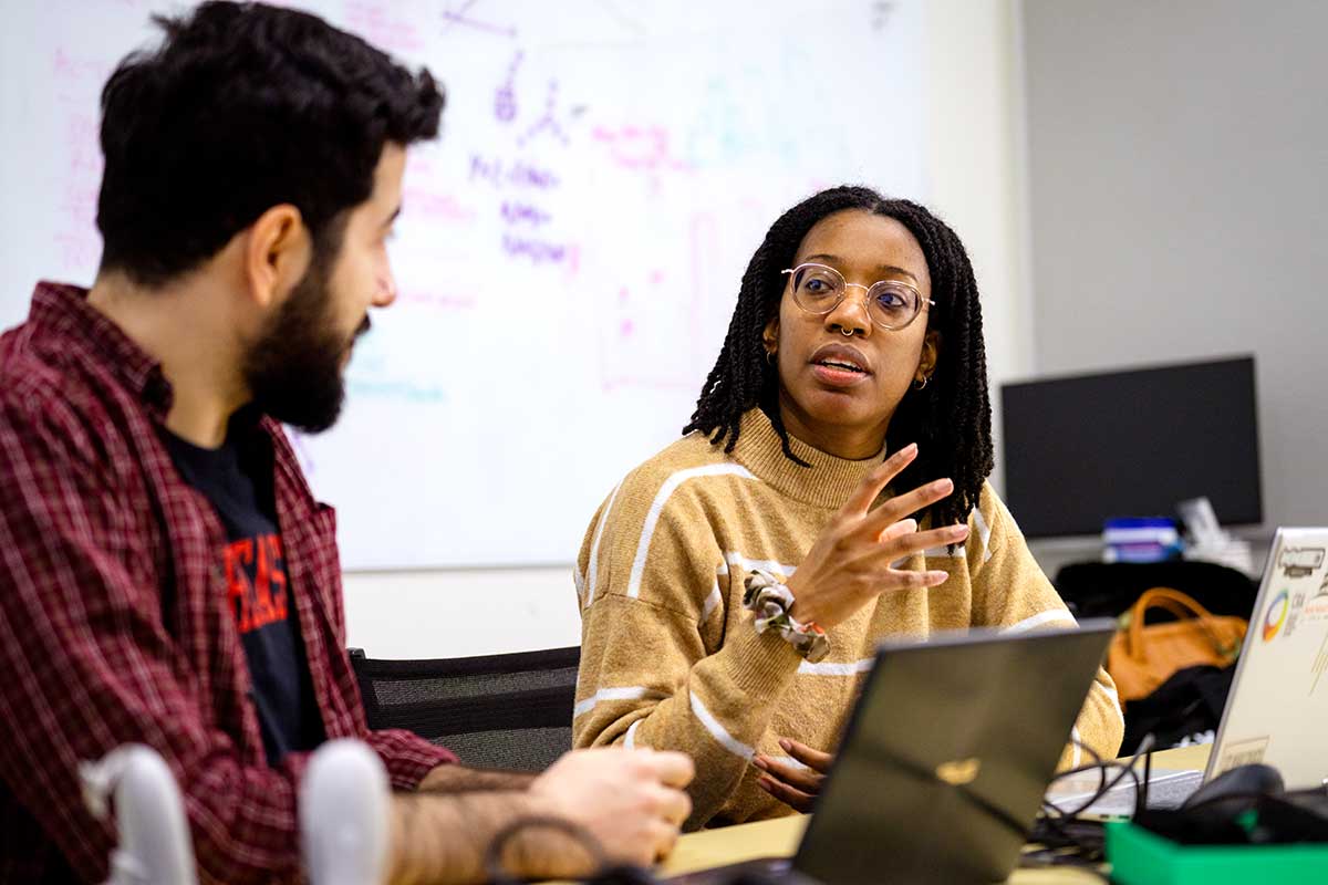 Two Khoury researchers sit at a table and have a discussion