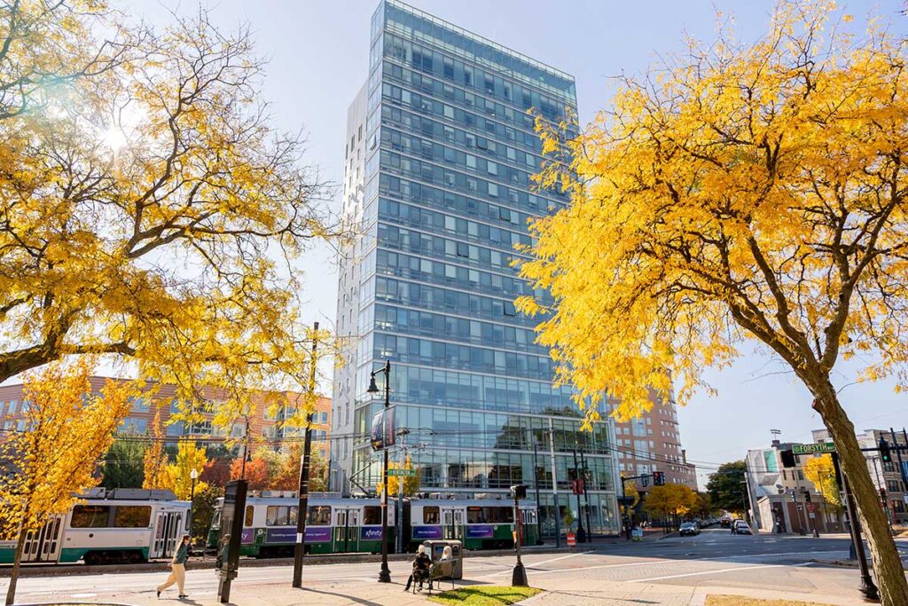 A view of West Village H framed through two trees with yellow leaves