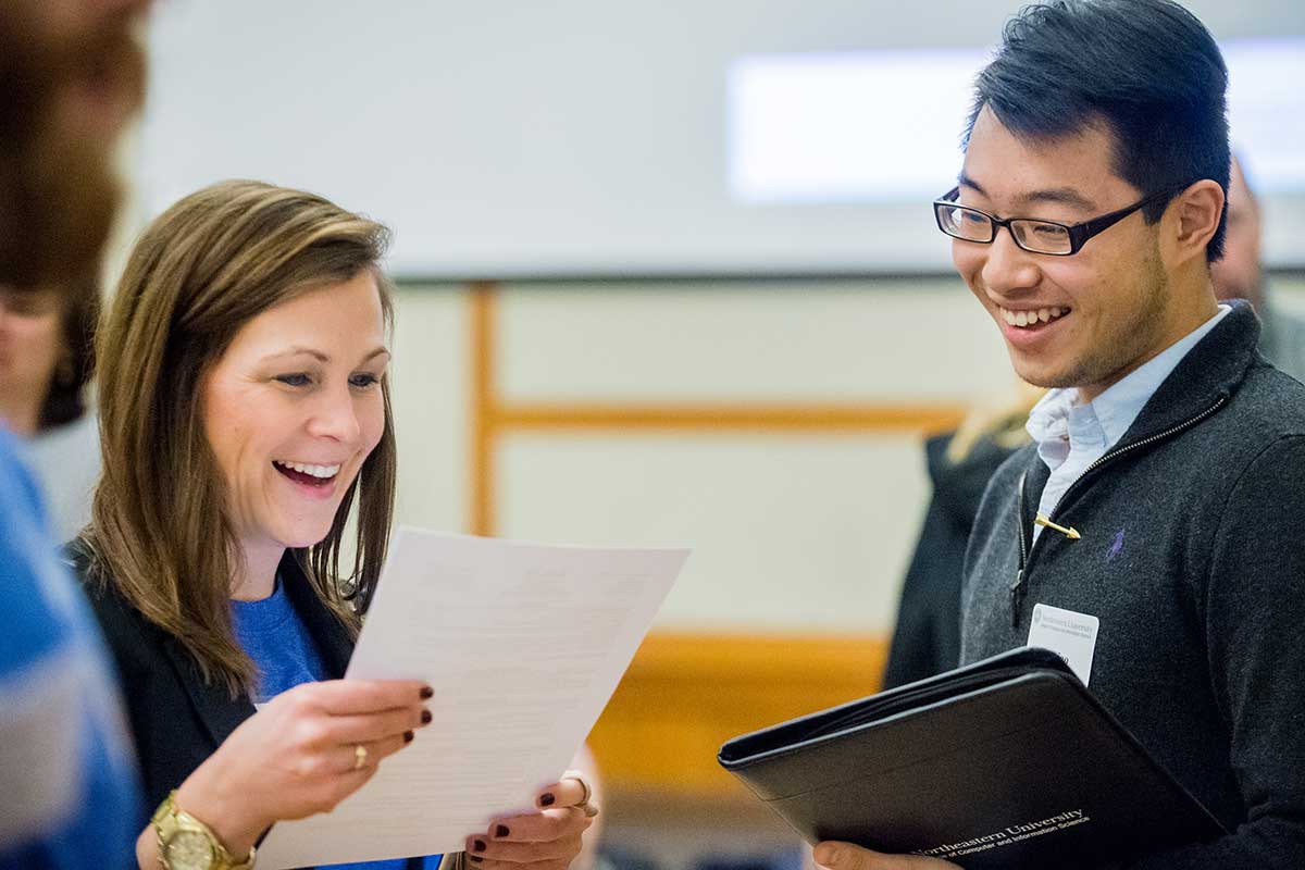 An employer looks at a student's resume during an employment fair