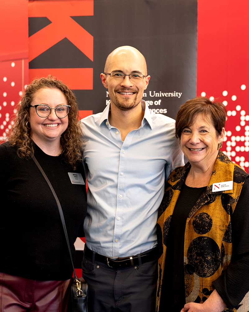 A Khoury alum (center) poses for a photo standing between Khoury staff members