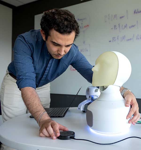 A Khoury researcher gives a hug to a robotic device that resembles a human face