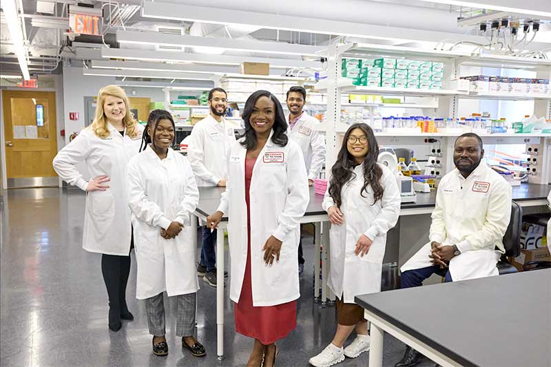 Shannen Espinosa (second from right) smiles and poses with her supervisor and colleagues in the Harvard biomedical lab