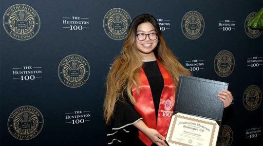 Shannen Espinosa smiles and shows her Huntington 100 award certificate