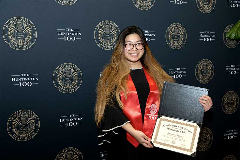 Shannen Espinosa smiles and shows her Huntington 100 award certificate