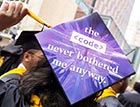 A graduate shows the back of a graduation cap with a sign that says 'the code never bothered me anyway'