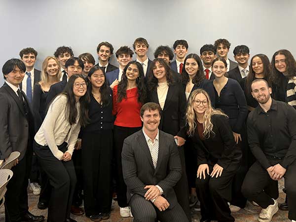 About 25 members of Kappa Theta Pi pose for a photo in a classroom