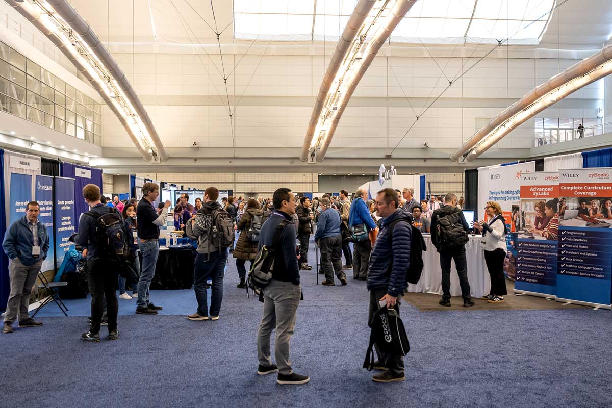 A photo of a conference hall filled with people talking in groups