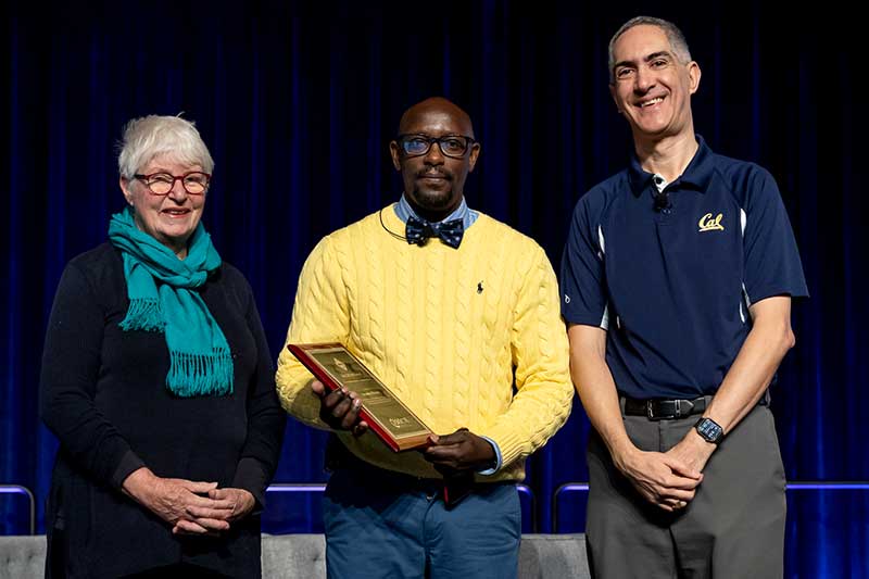 Khoury faculty Jonathan Mwaura (center) holds an award while standing between two people at SIGSCE
