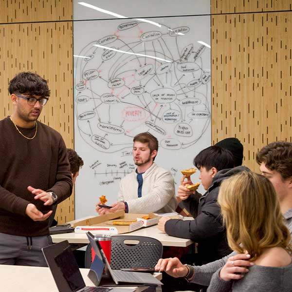 A club member speaks with a two students sitting at a table