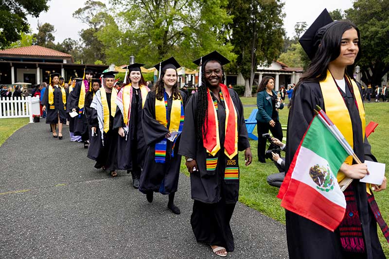 Khoury graduates walk to their seats in a single-file line