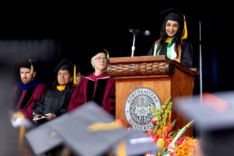 An Oakland graduate speaks behind a podium on the stage