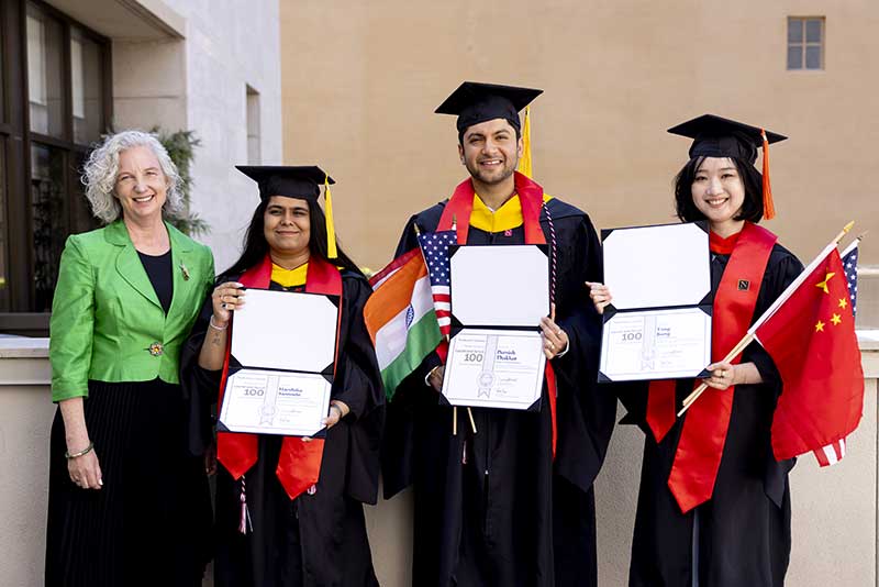 The Silicon Valley dean (left) stands with three Khoury graduates holding their diplomas open