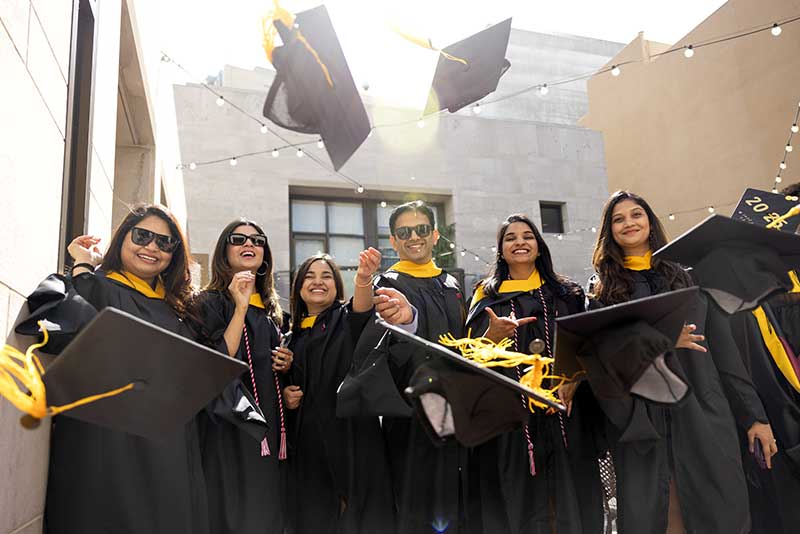Six Khoury graduates toss their caps into the air