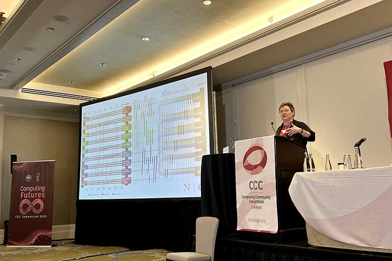 Mynatt speaks at the Computing Research Association’s Future Research Symposium, with the “tire tracks” visualization to the left.