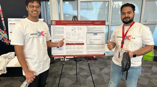 Isaac Premkumar and Ishan Chaudhary stand beside their research poster