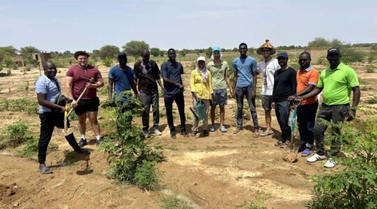 Jonathan Mwaura stands with 11 members of his group in a field in Senegal