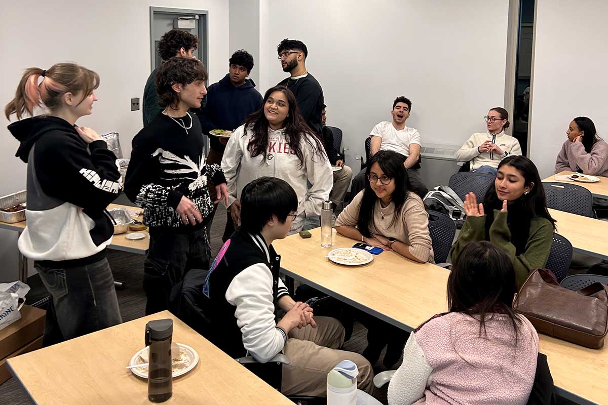 Students talk while sitting around large tables in a Northeastern classroom