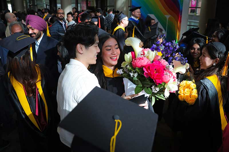 A Khoury graduate holds a colorful bouquet of flowers