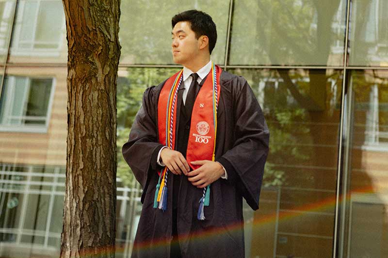 Jeff Pan poses while wearing his graduation robe and a red sash