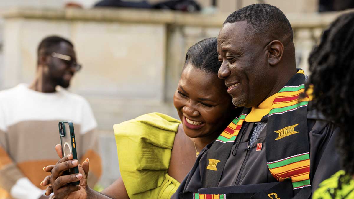 A graduate takes a selfie with a ceremony attendee