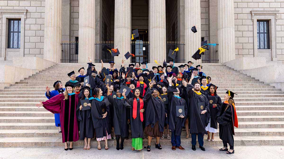 Dozens of graduates from Khoury College programs in Arlington toss their graduation caps in the air