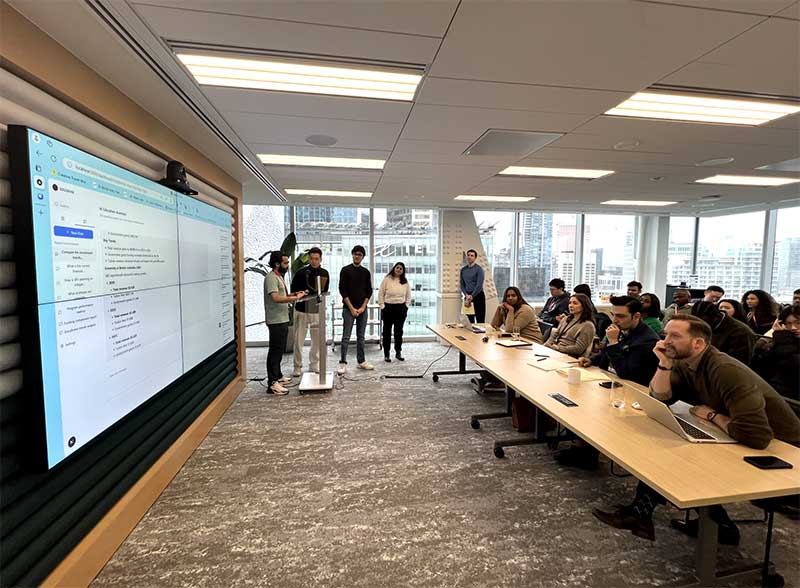 One of the hackathon teams presents a project on a large screen at the front of a conference room