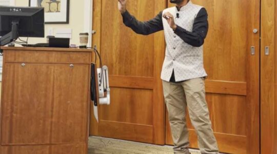 Upol Ehsan stands at the front of the room while giving a lecture