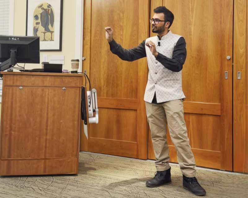 Upol Ehsan stands at the front of the room while giving a lecture