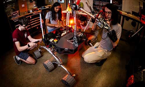 Four Northeastern students work on their Mars Rover robot in a Northeastern lab. Photo by Alyssa Stone/Northeastern University