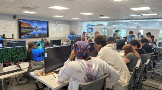 Middle and high school students sit at desks and work on their assignments during GenCyber camp