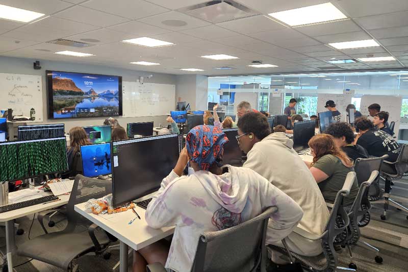 Middle and high school students sit at desks and work on their assignments during GenCyber camp