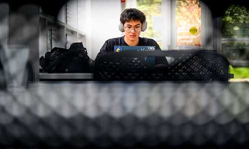 A Khoury student types on a laptop while working in West Village H