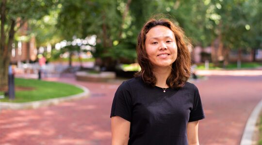 Photo of Khoury PhD student Hye Sun Yun set against a backdrop of bricked sidewalk and trees.