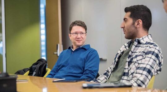 Engin Kirda (left) and Seyed Ali Akhavani discuss a project while sitting at a table