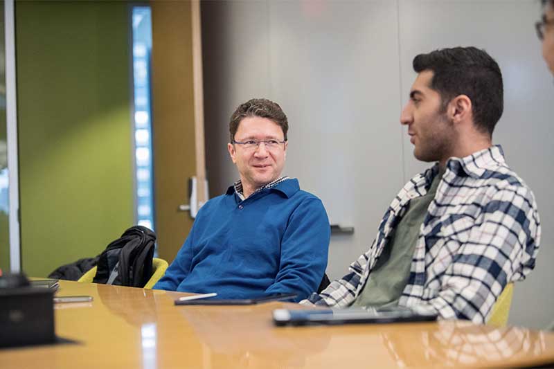 Engin Kirda (left) and Seyed Ali Akhavani discuss a project while sitting at a table
